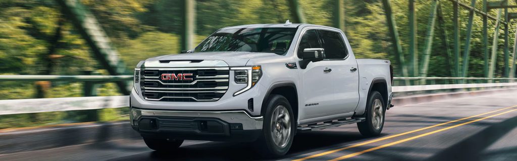 2026 GMC Sierra 1500 driving on a tree-lined road