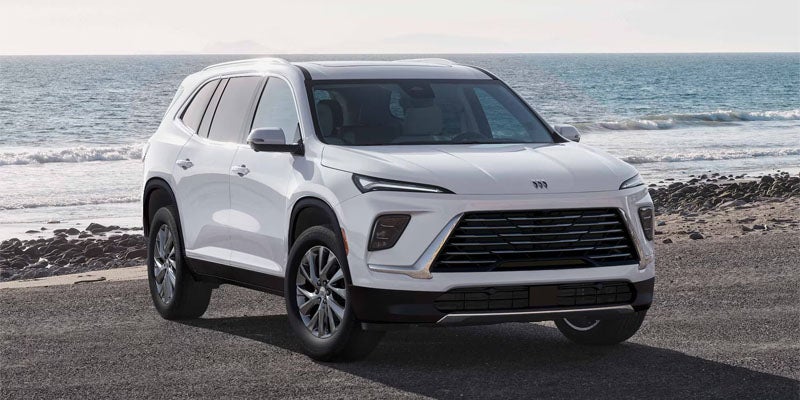 Forward-facing white 2026 Buick Enclave near water at sunset